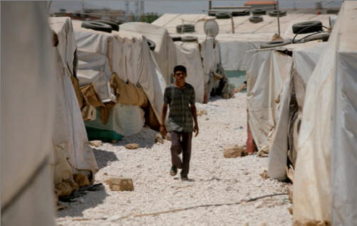 Ragazzo siriano passeggia tra le tende del campo Dalhmieh a Zahle, Bekaa valley, Libano.  Caritas Internationalis/Matthieu Alexandre 